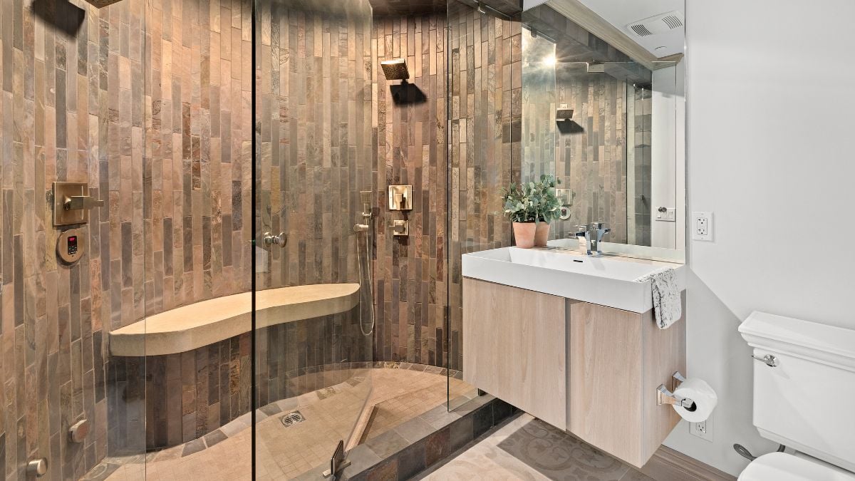 A closer look at the glass door separating the shower area from the tiny sink and toilet.