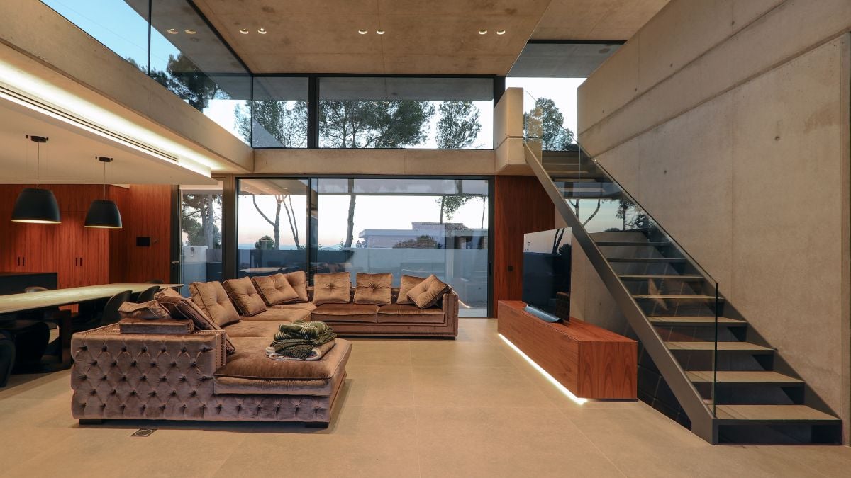 An interior photograph captures the sophisticated design of a living space, bordered by glass panels, and features a striking staircase on the side.