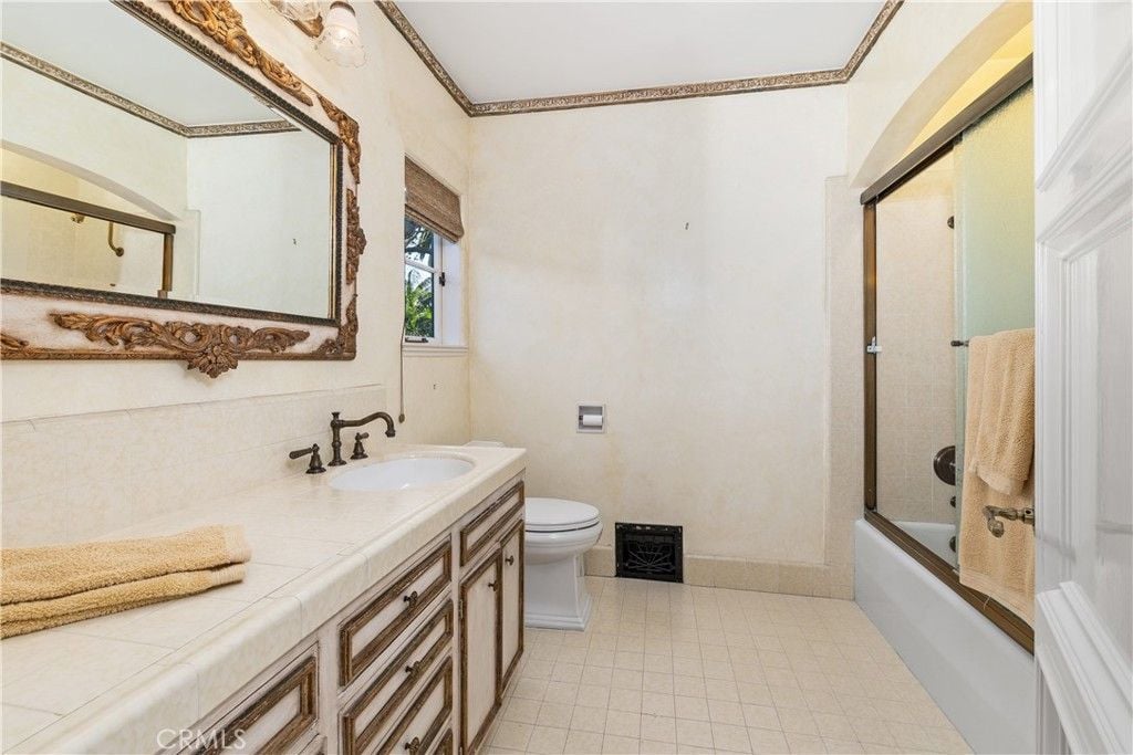 The bathroom features a vanity with a tile countertop and a drawer with a wooden outline giving the room a luxurious feel.
