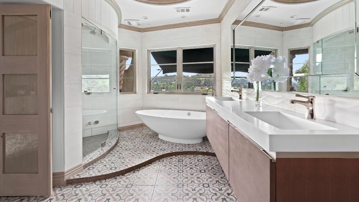 The bathtub, sink with a large mirror, well-designed ceiling, and flooring all contribute to this bathroom's chic appearance.
