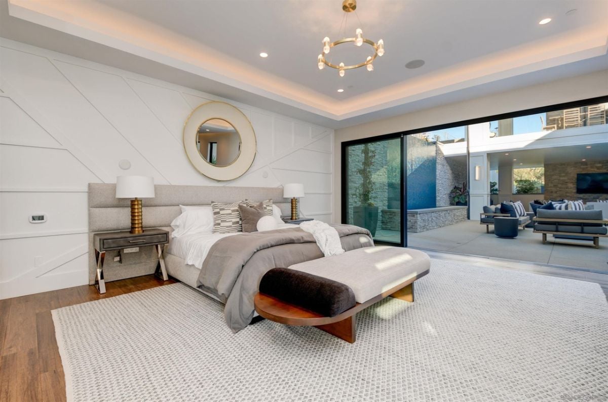 The bedroom features a wooden bench and a glass door that gives access to the patio.