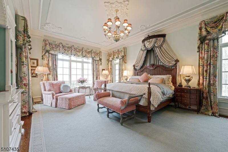 The master suite features a wooden bed, a bedroom bench, and a nightstand giving the area a luxurious feel.