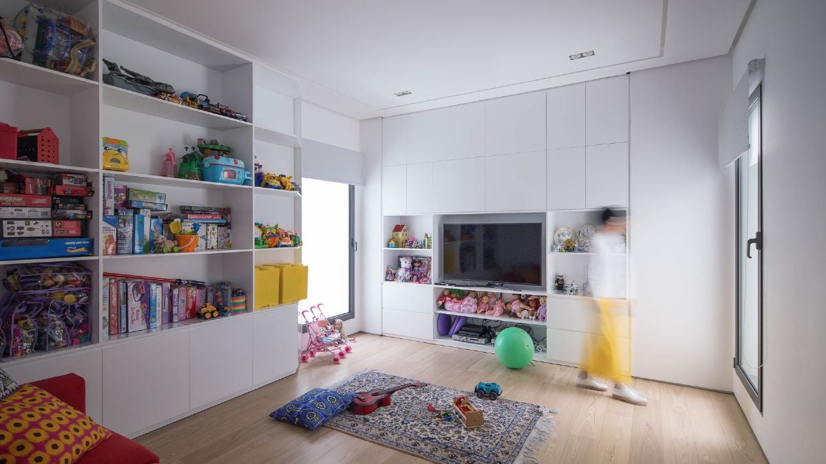 The spacious kids' room has numerous shelves and cabinets, as well as a large glass window for natural light.