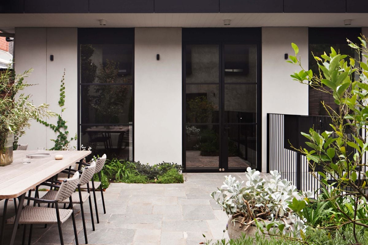 The backyard has an outdoor dining area and plants that cool the surrounding.