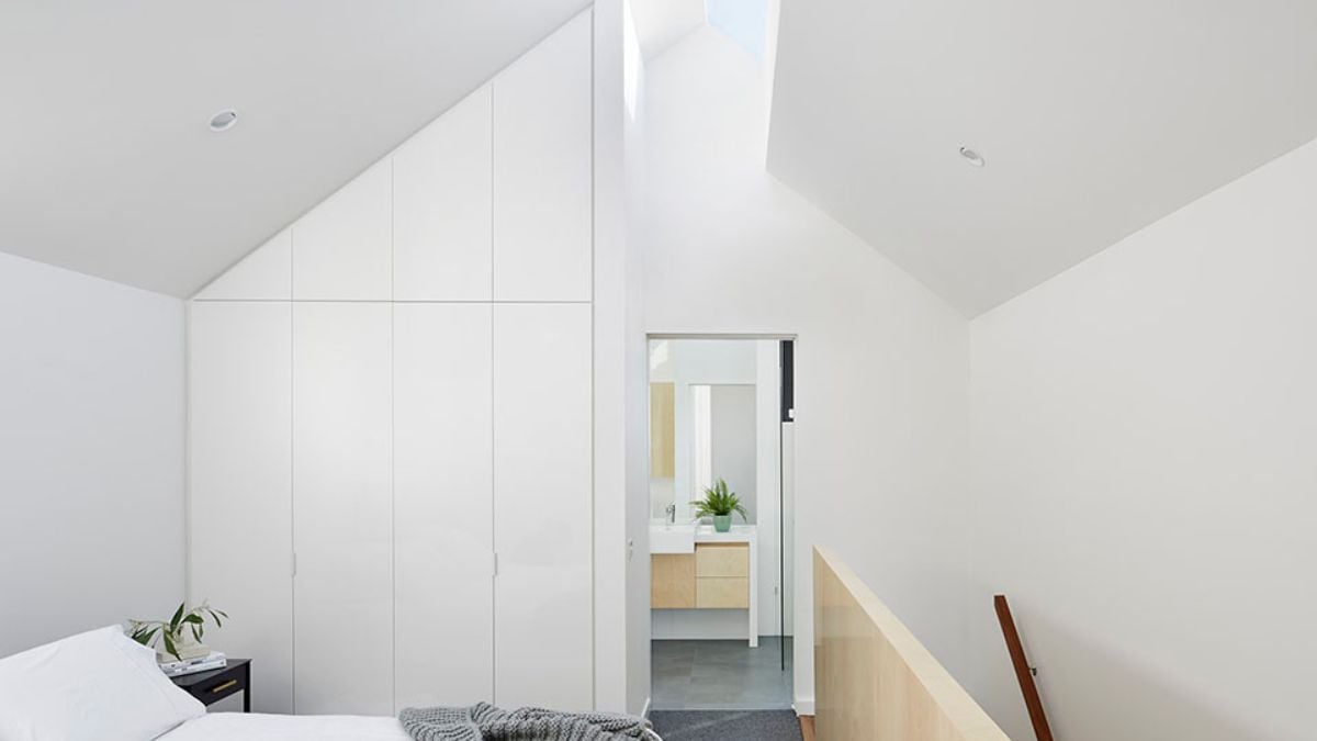 This photograph provides a perspective view of the bedroom, with a focus on the wide white cabinet and a partial view of the bed.