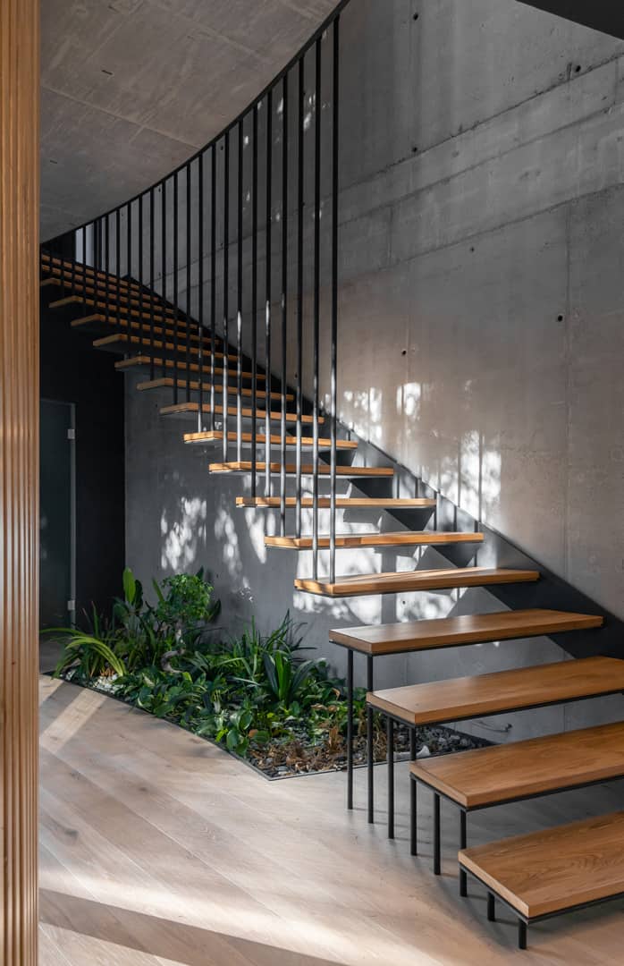 Beneath the stairs is an indoor pocket garden adorned with lush plants and pebbles.
