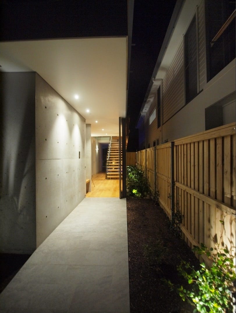 A wooden fence complemented with green plants provides privacy at the home's entrance.