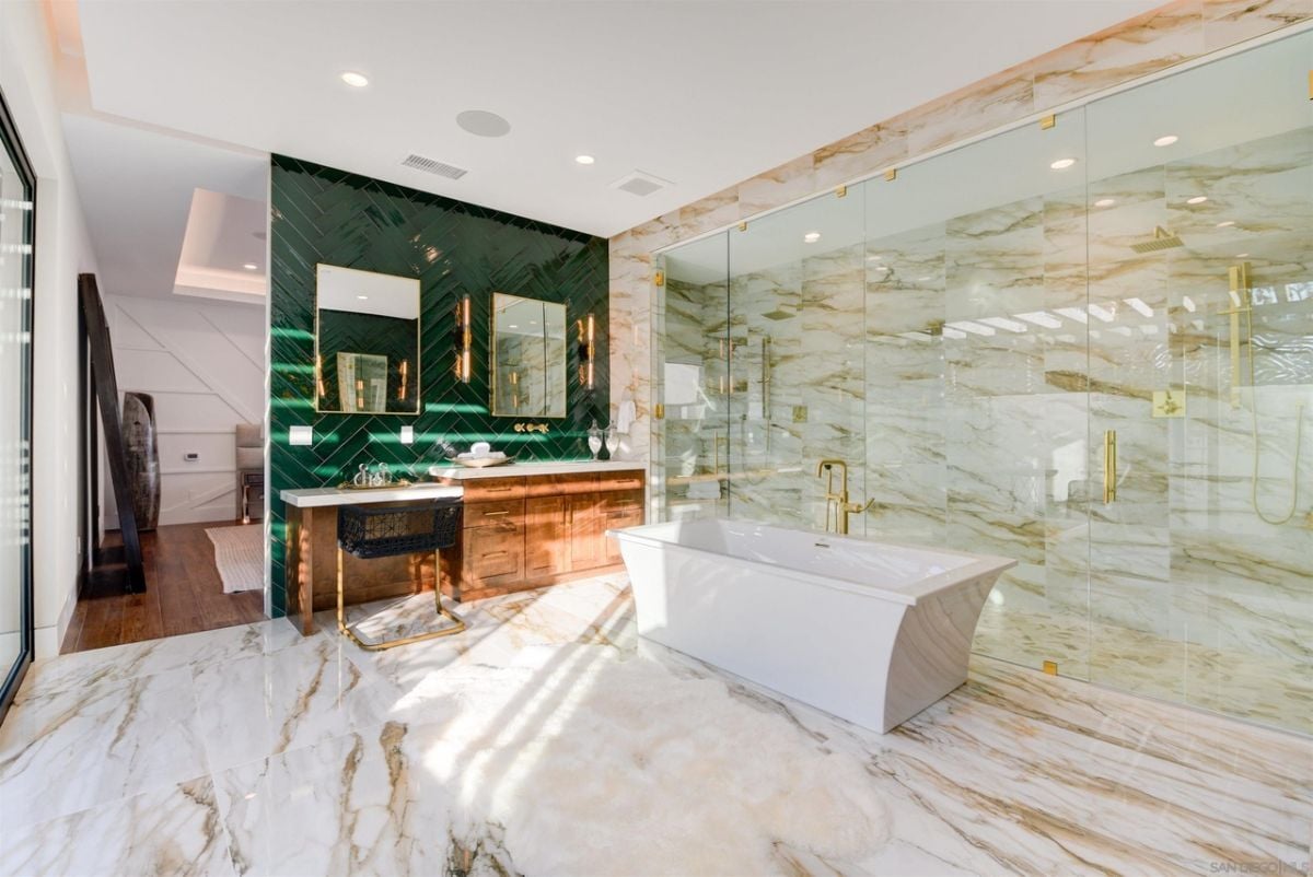 The bathroom features a free-standing bathtub and a glass cubicle for the shower.