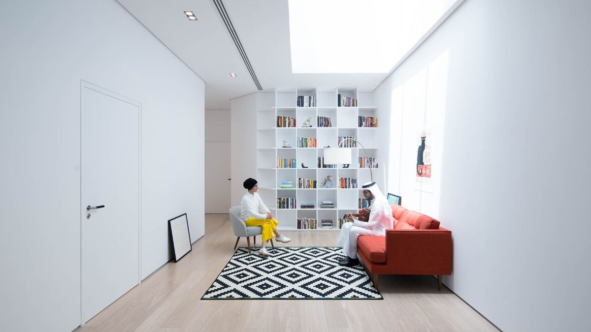 Spacious entertainment room with wall shelves and red sofa for guests.