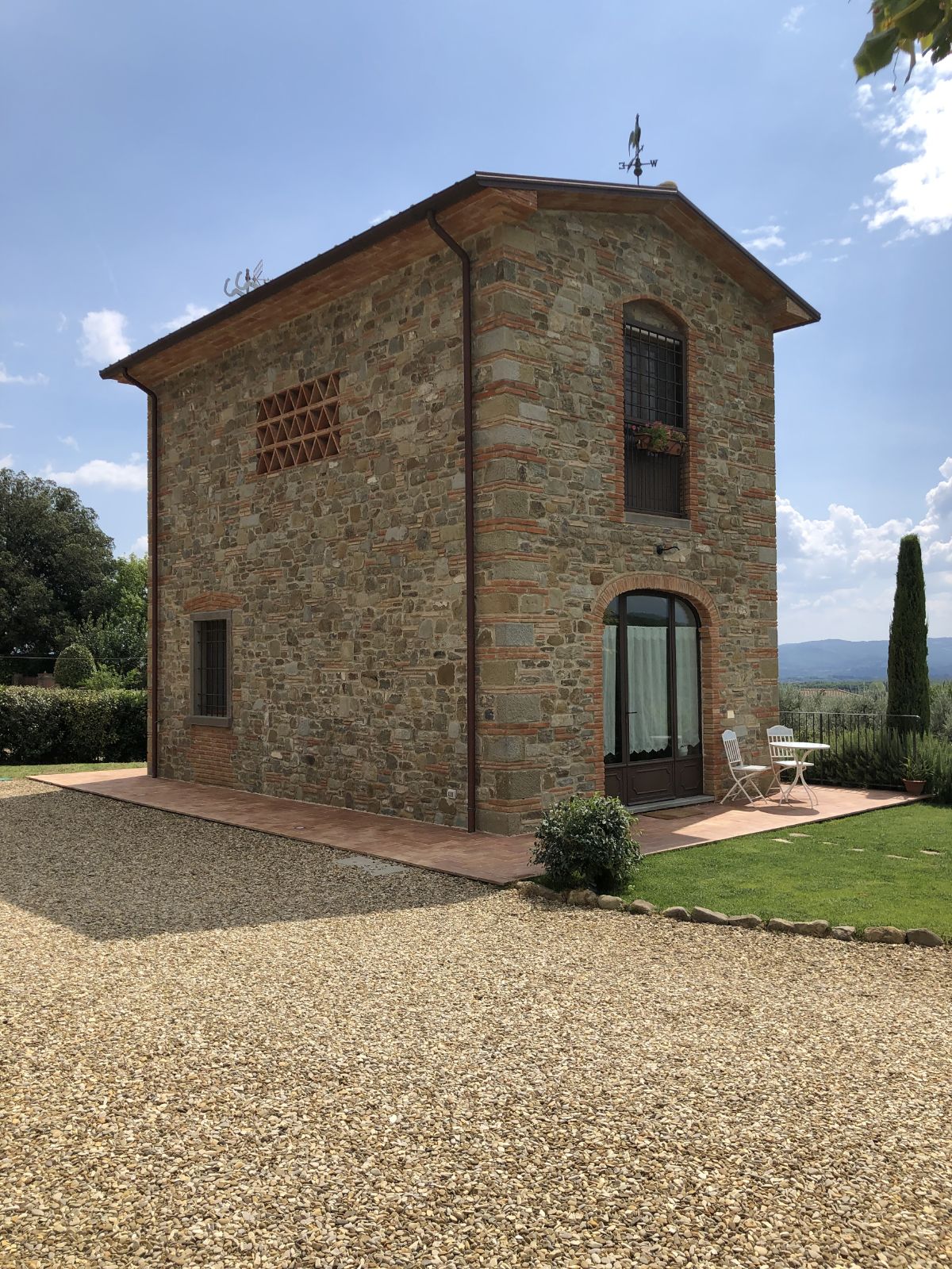 The house is made of stone wall with a brick walkway and a driveway made of gravel.