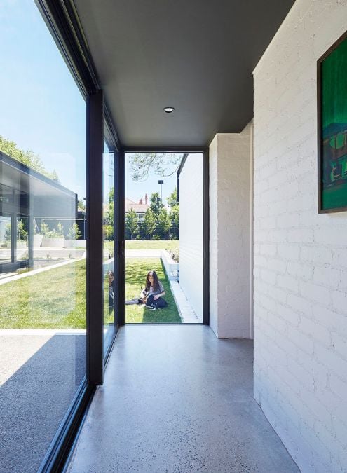 This describes a narrow path leading outdoors that is enclosed by a full-height glass wall.