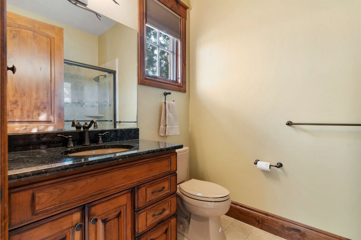 The bathroom features a vanity with a granite countertop and wooden drawer that gives the room a rustic feel.