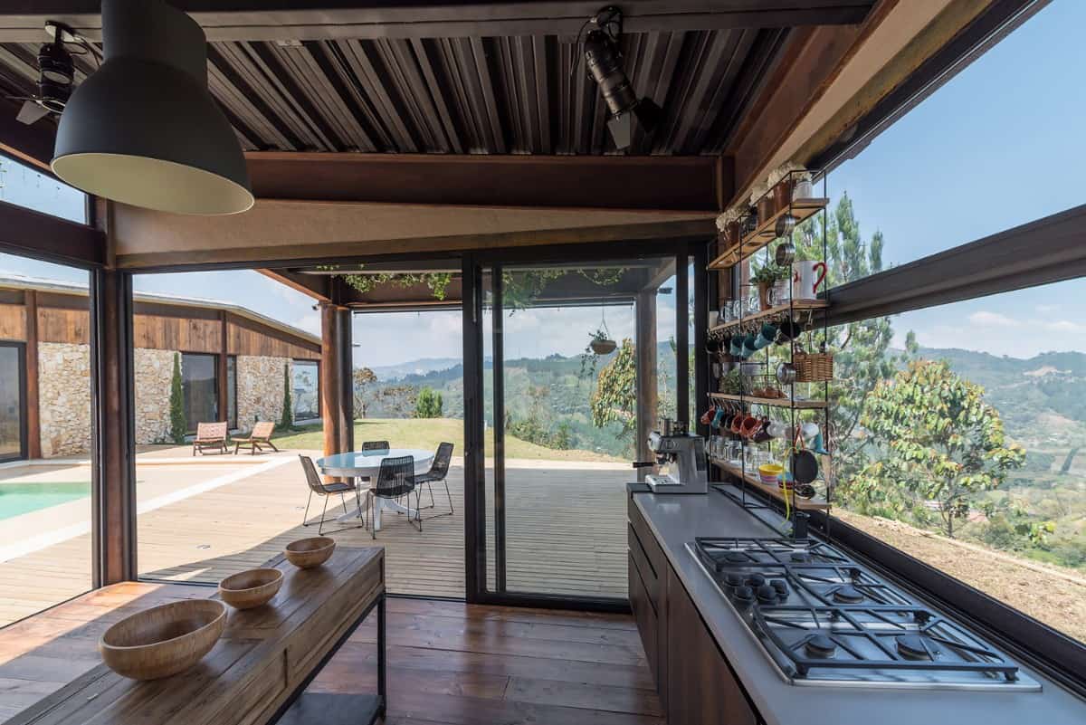 The kitchen has stunning views of the outdoor living and the surrounding landscape.