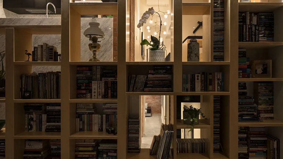 A large wooden bookshelf with a variety of books on it can be seen in this home.