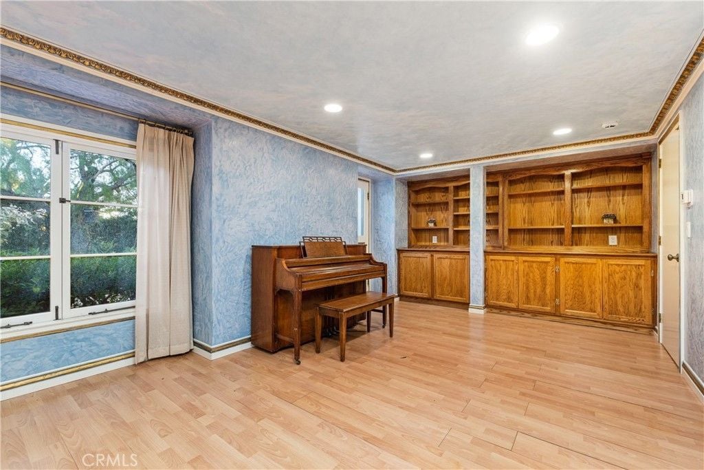 The music room features a piano and shelves that blends well with the flooring.