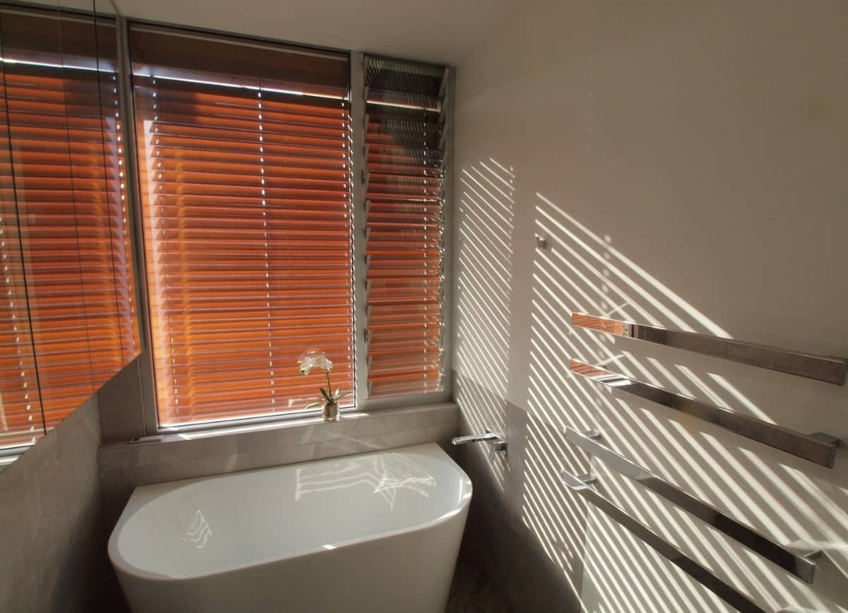 Natural light streams into the bathroom through the shuttered windows.