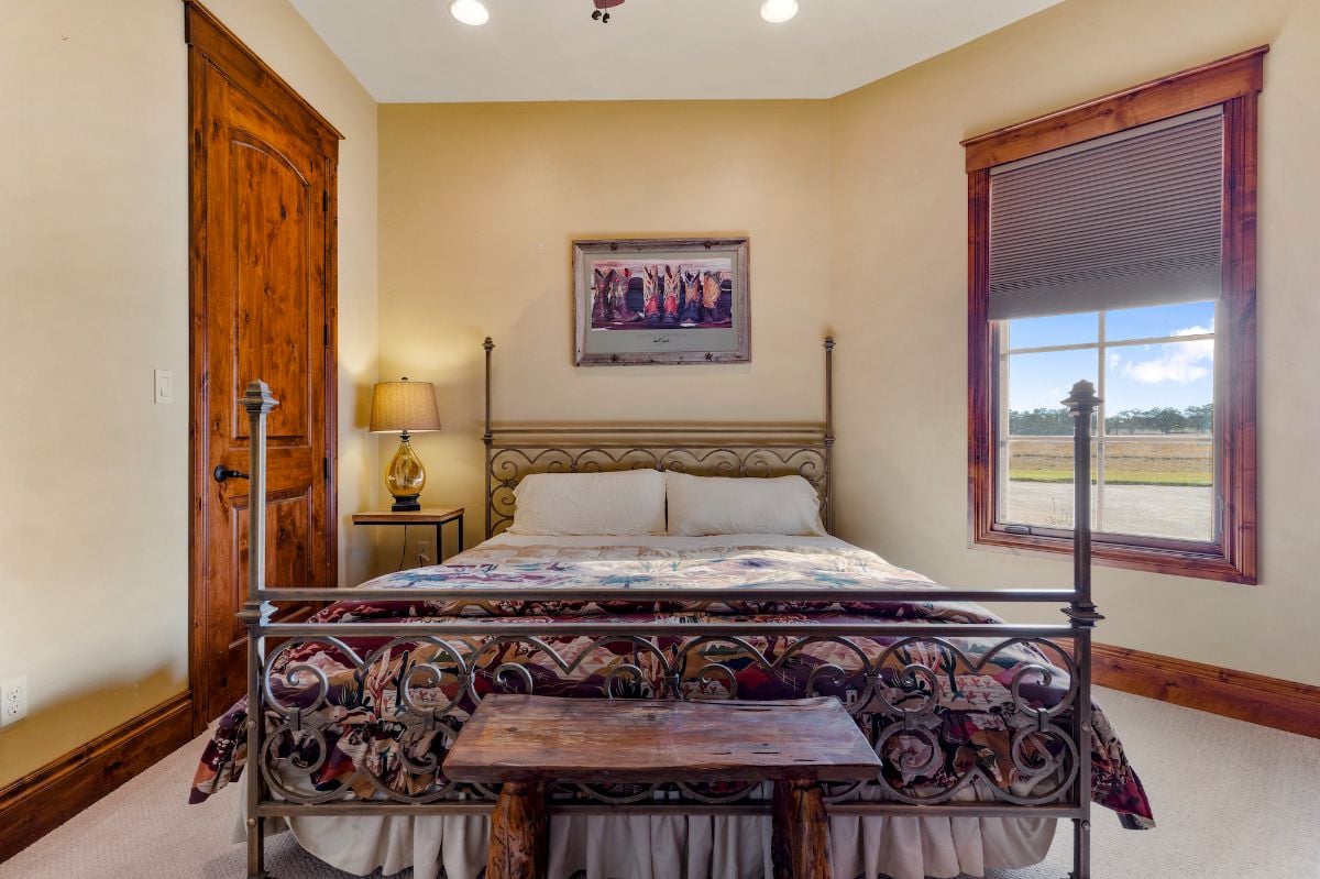 The bedroom features a wooden bedroom bench and a metal bed that gives off a luxurious feel.