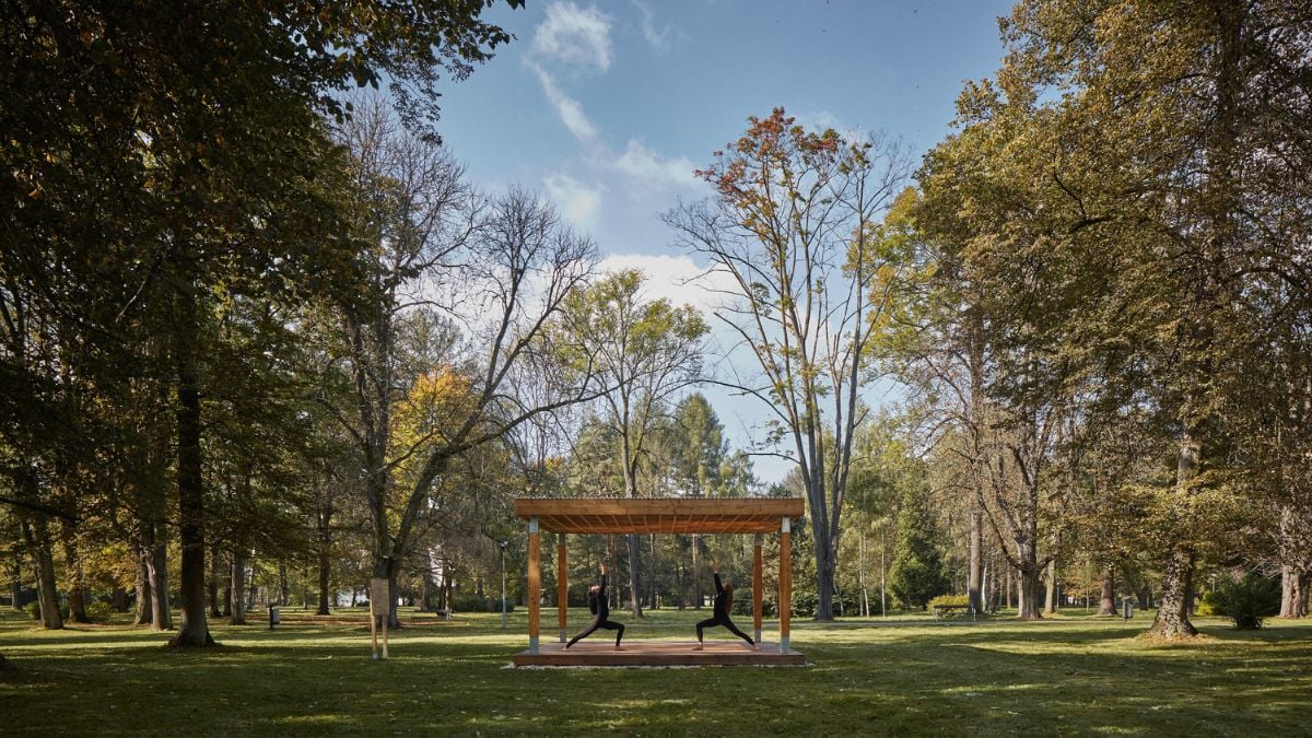 This photo offers a view of the larger Yogapoint structure from a distance, while also highlighting the lush green surroundings of the area with trees.