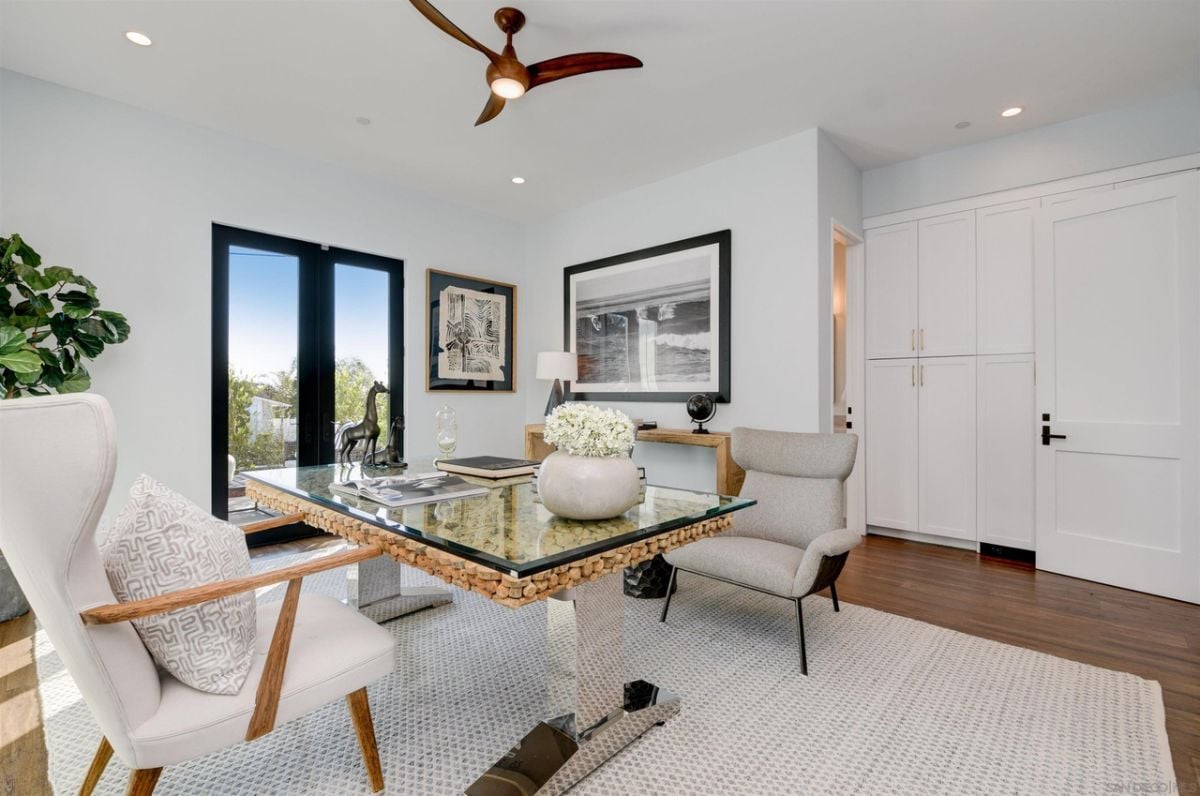 The study features a glass office table and an area rug that gives a professional look to the room.