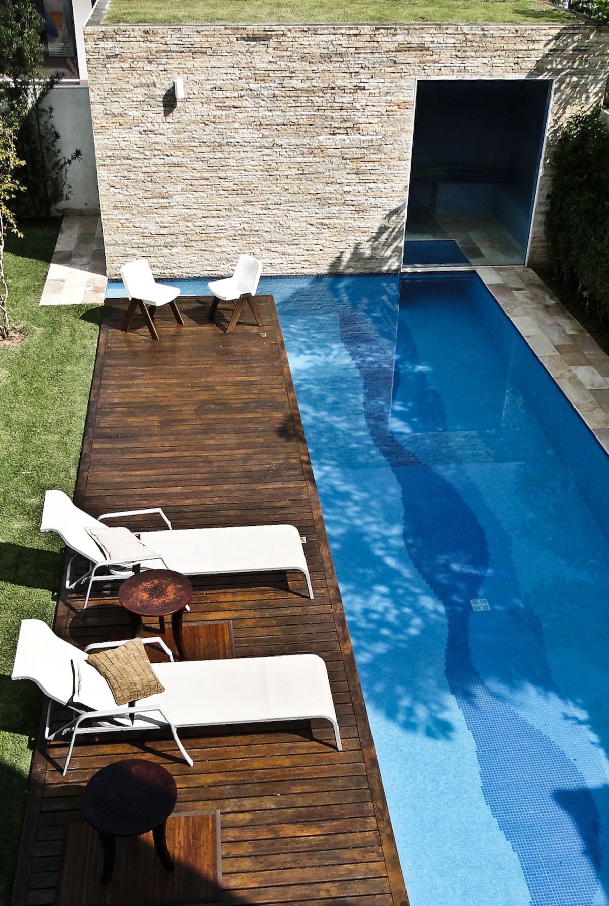 The pool area features a wooden deck and sunlounger for relaxation.