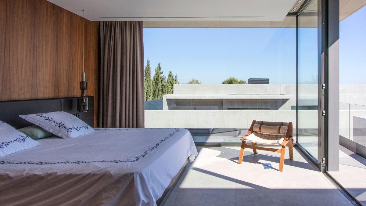 A photo showcases the interior design of a bedroom that is enclosed by an expansive glass panel.