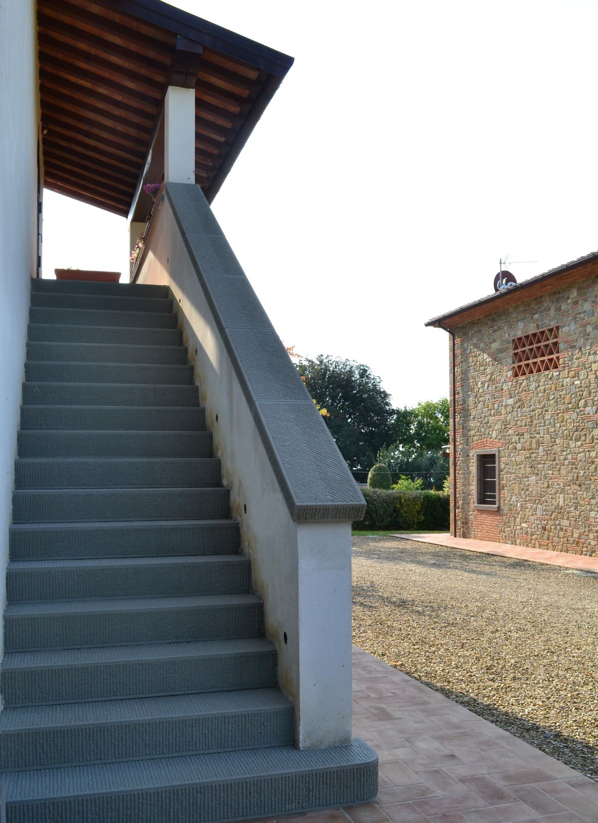 The entrance to the house features concrete stairs and a brick walkway.