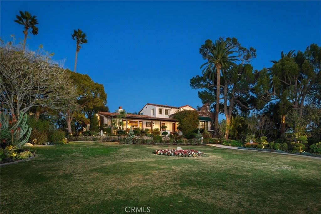 The house features a lawn with surrounding by plants and fountains.