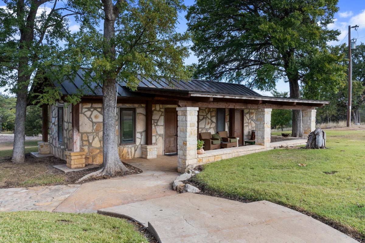 A concrete walkway leads to the guest house surrounded by trees.