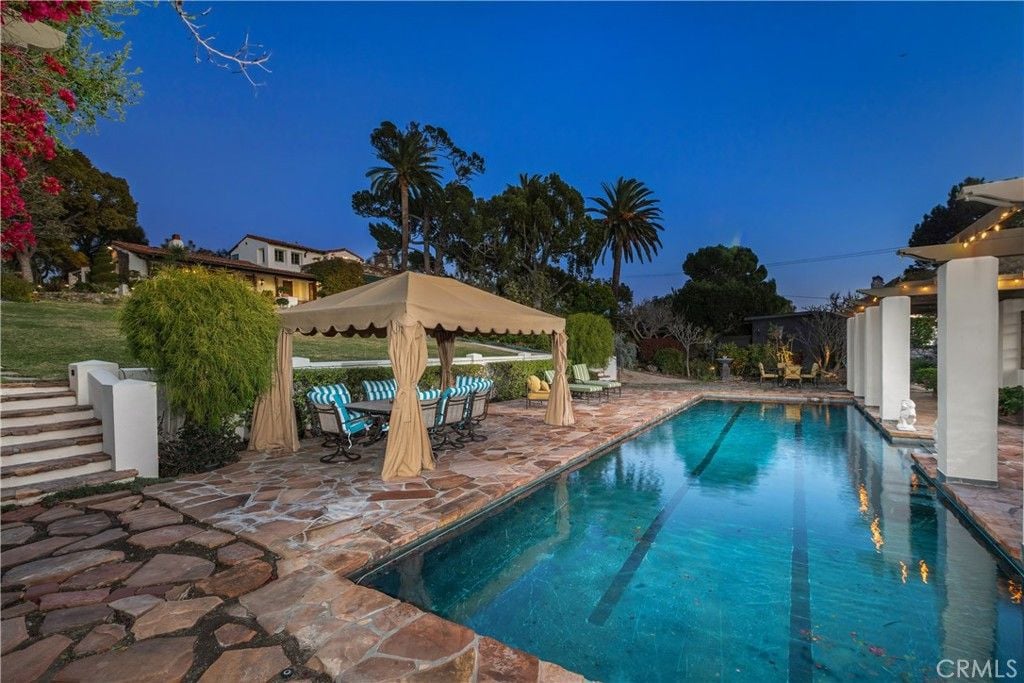 A canopy shades the outdoor dining area beside the swimming pool.