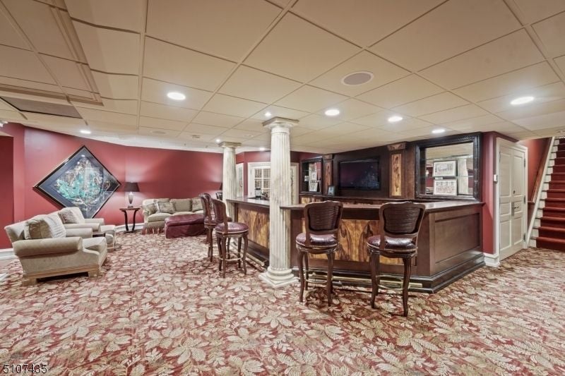The wet bar features a wooden counter and Doric pillars giving off a classic feel.