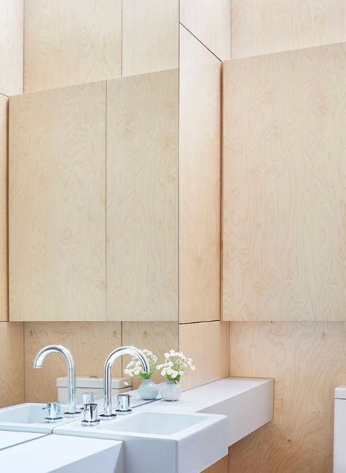 A detailed photograph of a sink station in a bathroom, highlighting an expansive vanity mirror and light brown cabinets.