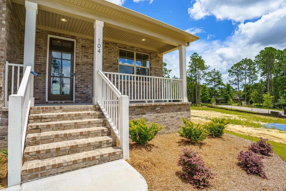 A closer look at the covered entry porch with a brick stoop and a glazed front door.