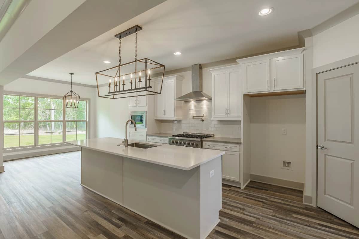 Across the kitchen is the keeping room brightened by a rear wall of windows.