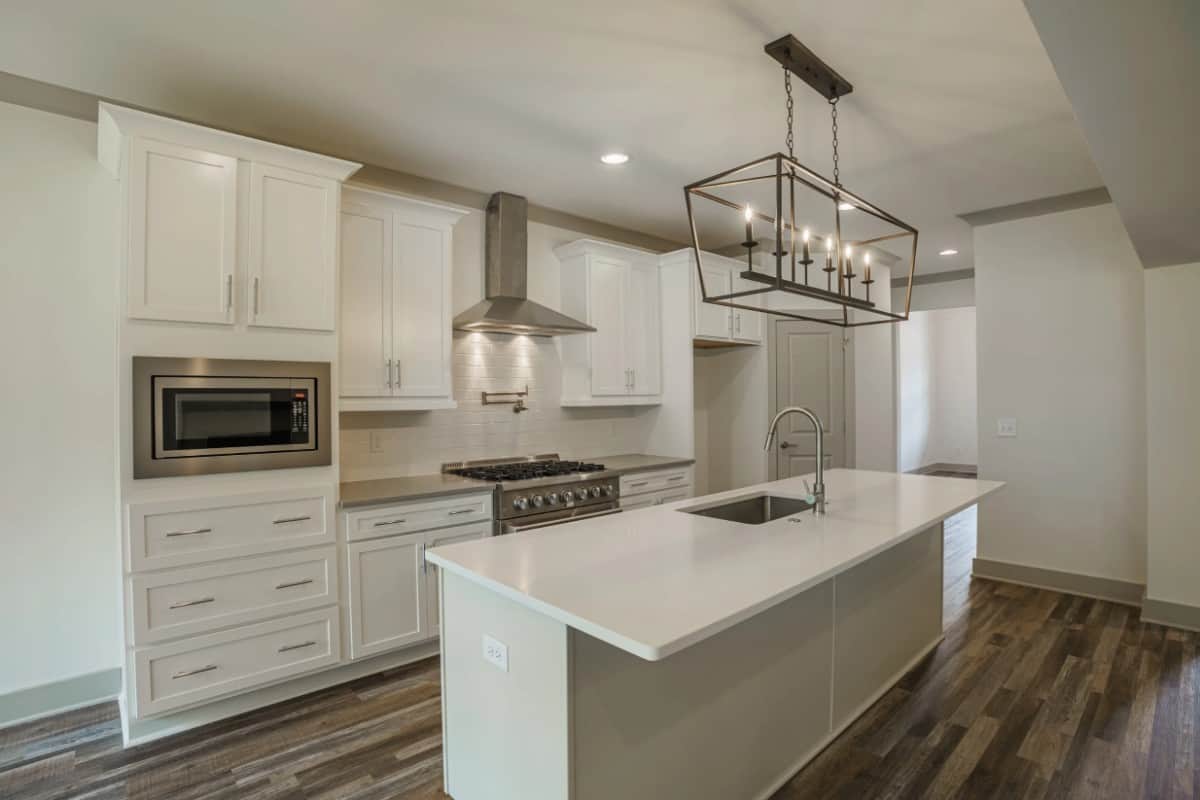 The kitchen has white cabinetry, stainless steel appliances, and a breakfast island fitted with an undermount sink.