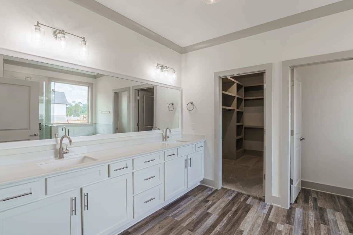 The primary bathroom includes a lengthy vanity with his and her sinks, and a walk-in closet with carpeted floor.