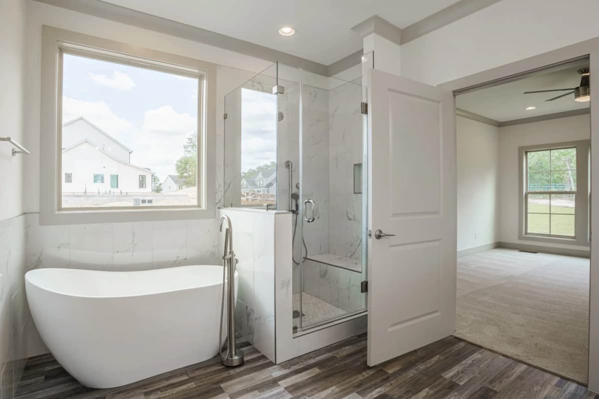 Primary bathroom with a walk-in shower and a deep soaking tub situated under the picture window.
