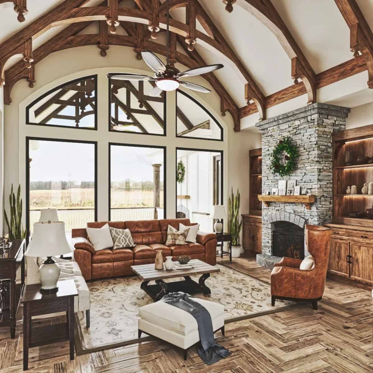The lodge room includes white and brown leather seats, a stone fireplace, wooden built-ins, and massive windows that look out the back porch.