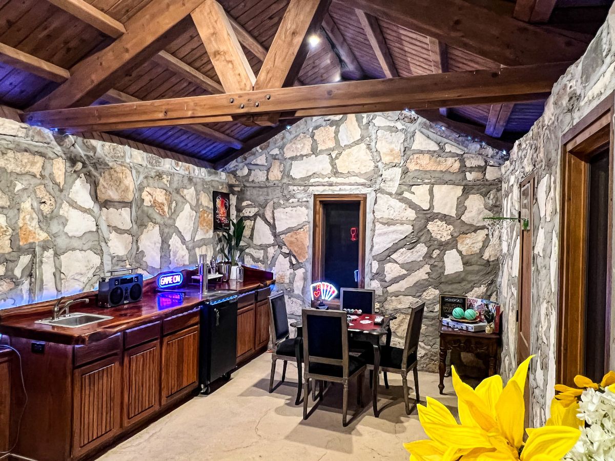 The guest house features a kitchen-dining area, and the exposed wooden beams give the room a rustic feel.