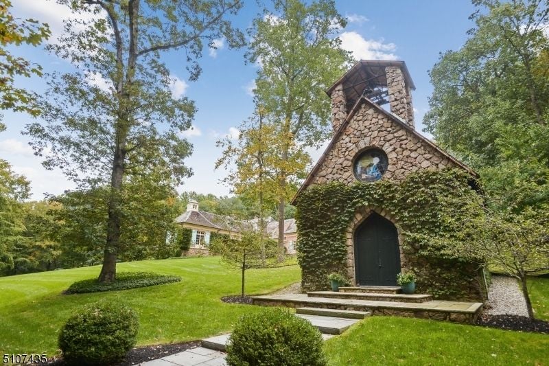 Outdoors is a chapel with a stone wall and a concrete walkway.