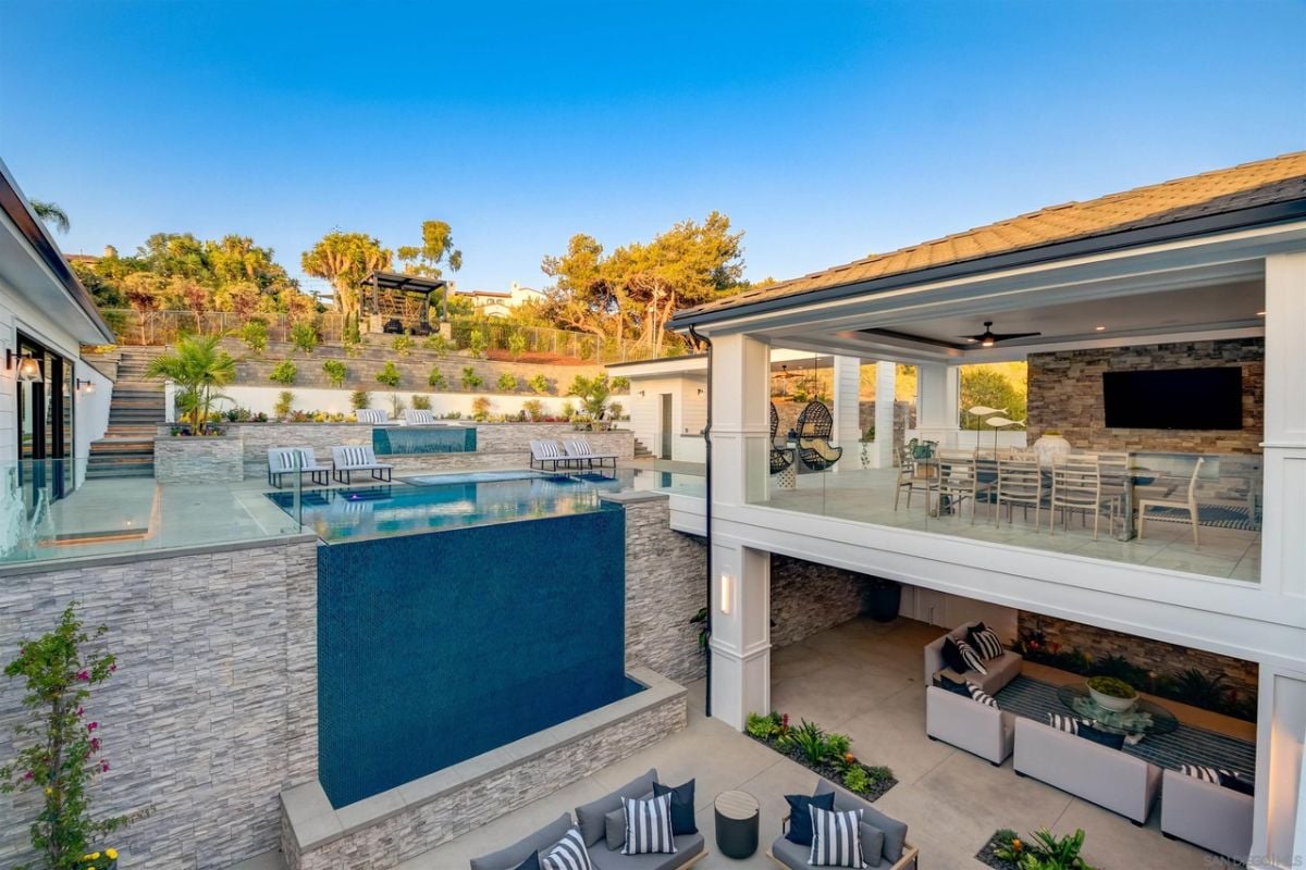 The swimming pool in the backyard overlooks the outdoor patio.