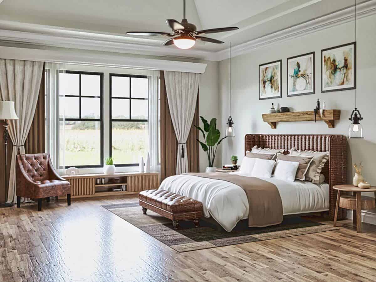 The primary bedroom features a wicker bed with a tufted bench on its end and a sitting area by the rear windows.