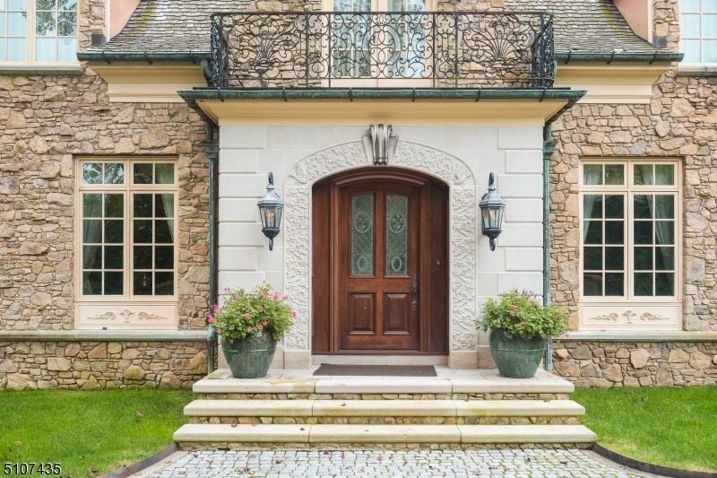 The house entrance features concrete slabs with a stone paved way.