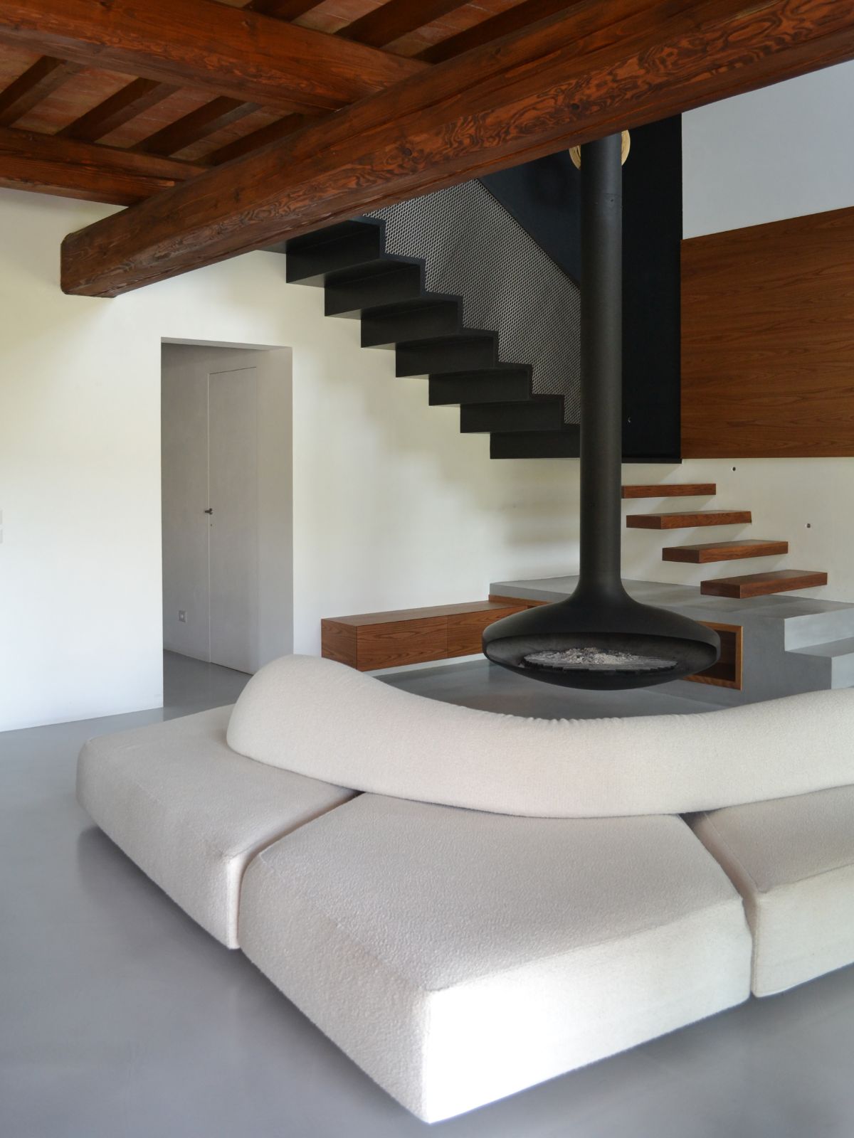 The living room features a hanging fireplace and a sectional sofa.