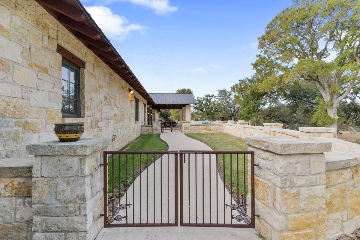 A metal gate and a concrete walkway leading to the covered porch.