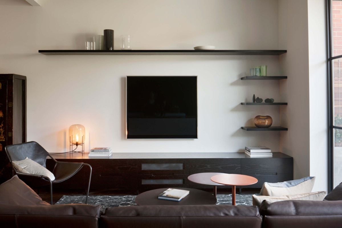 The living room features a leather sofa and carpet, giving off a cozy feel.