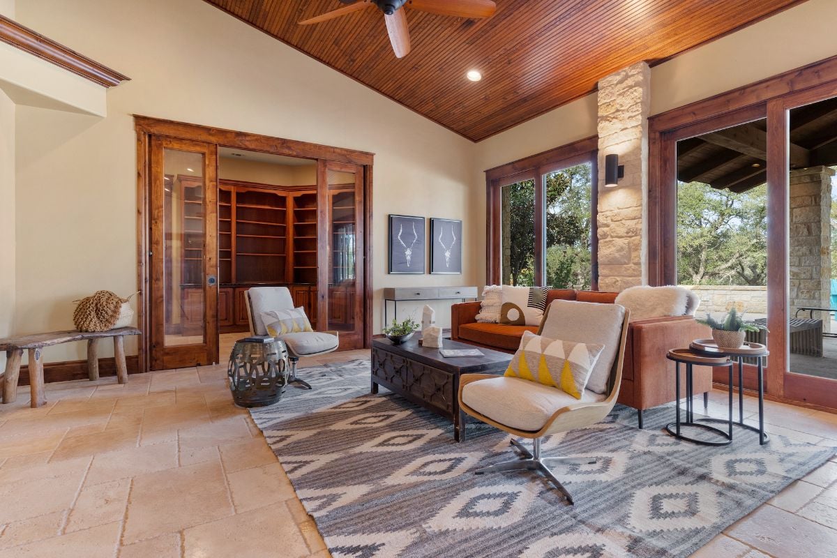 The living area features an ottoman table and sofa. The concrete flooring and the wood give the room a rustic feel.