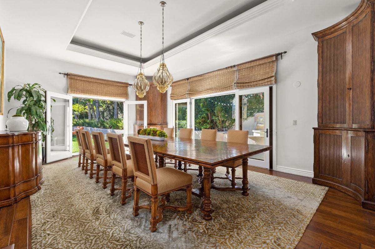 The formal dining room features a solid wooden table and large glass doors that serve as ventilation.