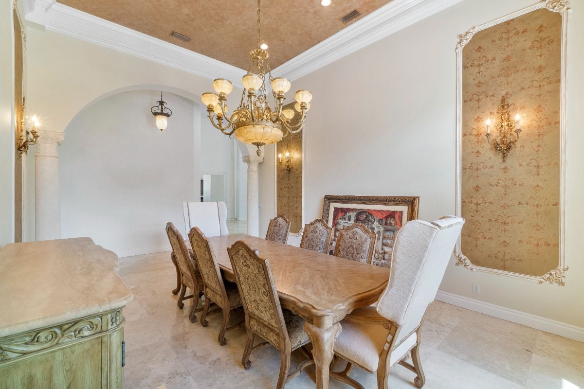 The dining room features an antique wooden table, and the gold-plated lighting gives the room a luxurious feel.