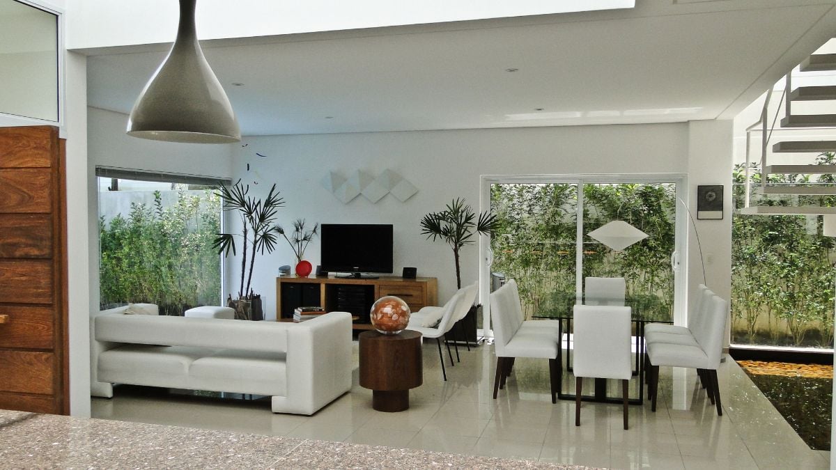 The living room sits next to the dining area, and the glass walls showcase the outside view.