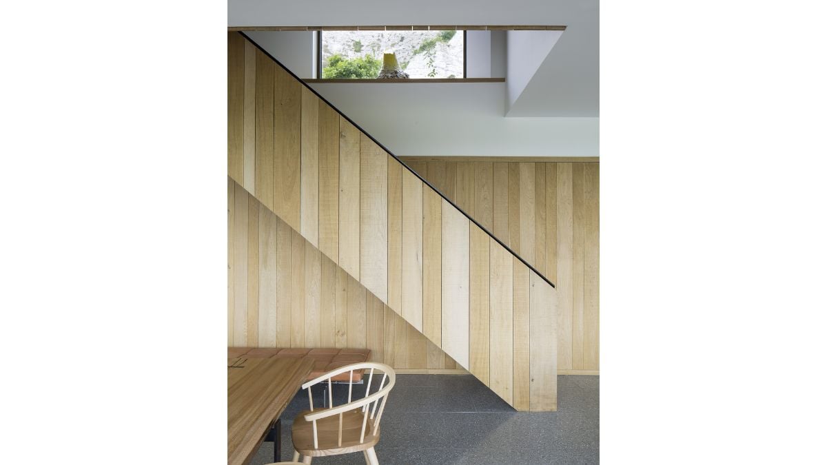 The wooden wall matches the wooden handrail of the staircase.